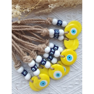Detail of yellow Turkish evil eye wall hanging with natural twine and blue beads