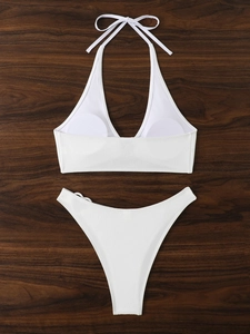 Flat lay di bikini bianco testurizzato con dettaglio a cuore su legno scuro
