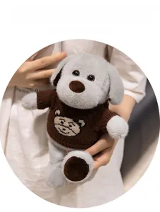 Détail d'un chien en peluche gris portant un pull en tricot marron avec ours