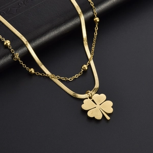 Elegante collana a doppio strato in oro con pendente a quadrifoglio su fondo nero