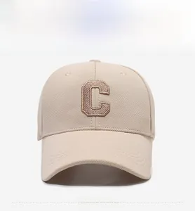Detail of premium 3D embroidered brown letter C on a beige cotton baseball cap