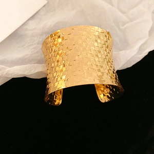 Detailed view of wide gold open bangle featuring intricate woven textured pattern