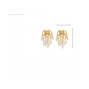 Detail view of golden firework tassel earrings with imitation pearls and alloy chains