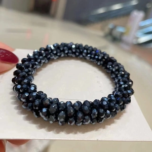 Detailed macro view of black faceted crystal beaded elastic hair tie and bracelet