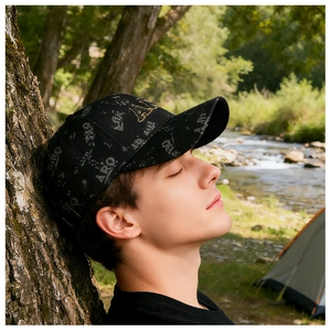 Vue en extérieur d'une casquette noire avec broderie AIRQ dorée et imprimé gris sur tout le tissu