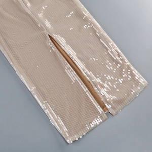 Detail of champagne sequin dress showing hem slit and shimmering mesh fabric texture