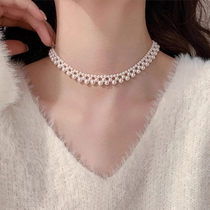 Detail of elegant double-layered woven pearl choker necklace worn with a white sweater