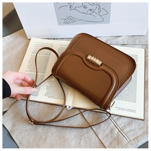 Détail du sac selle vintage marron avec fermoir doré sur fond de livre ouvert