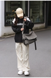 Male model wearing grey canvas messenger bag in urban street setting with casual outfit