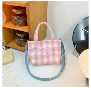 Detailed shot of pink plaid canvas children bag with a cute bow and blue strap