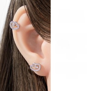 Detailed macro shot of silver wing earrings with micro-paved zircons on a model's ear.