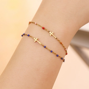 Detail of colorful beaded cross bracelets in gold finish on a female wrist