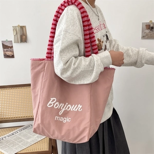 Detailed view of pink tote bag featuring a striped plush handle and Bonjour magic print