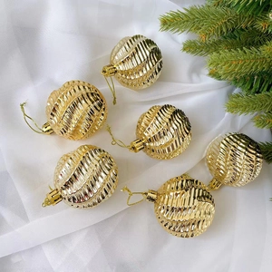 Sechs goldene geriffelte Weihnachtskugeln mit Schnüren auf weißem Stoffdekor