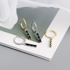 Macro shot of gold and silver rectangle zircon drop earrings on textured paper