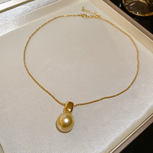Détail d'un collier de perles dorées sur soie beige dans un coffret à bijoux de luxe