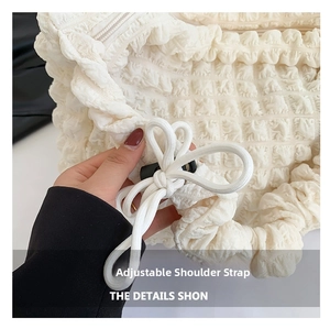 Detail of white seersucker cloud bag featuring an adjustable drawstring shoulder strap