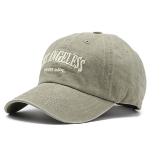 Close-up of white LOS ANGELES embroidery on washed green vintage cotton baseball cap