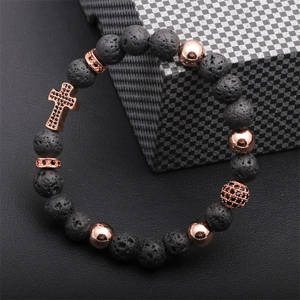 Macro detail of men's lava stone bead bracelet with rose gold cross and zircon ball