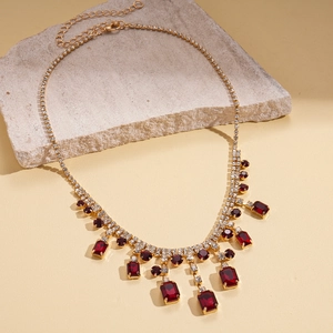 Detailed macro view of gold tassel necklace with red crystals and lobster clasp extension