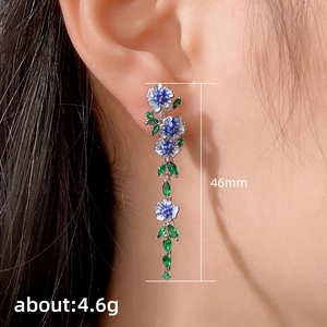Elegant long floral drop earrings with blue enamel flowers and green zircon on model