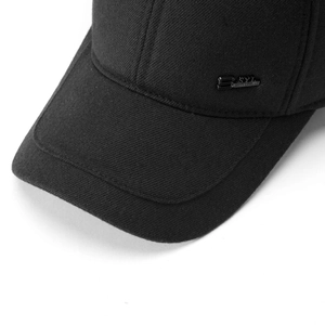 Detail of black cotton baseball cap showing textured fabric and metal logo plaque