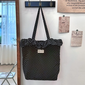 Detailaufnahme der schwarzen gepunkteten Segeltuchtasche mit Rüschenrand und Label