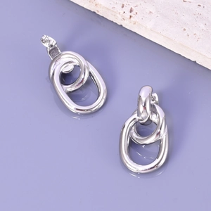 Détail macro de boucles d'oreilles ovales argentées entrelacées sur pierre lisse