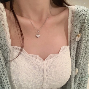 Close-up of double-layer silver heart necklace with crystal inlay on model's neck