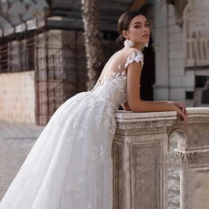 Elegant white lace wedding dress with floral embroidery and open back detail in outdoor setting