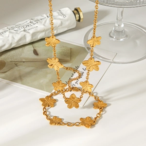 Detail of gold five-petal flower necklace with a brushed metal texture in soft natural light