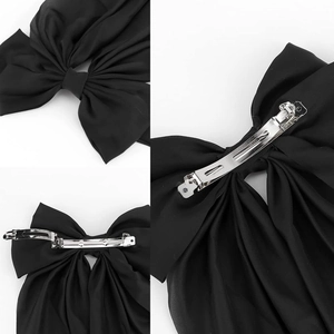Detail view of large black fabric bow hair clip with silver metal spring fastener
