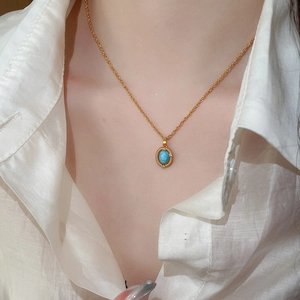 Close-up of French vintage gold necklace featuring a turquoise pendant with zircon accents