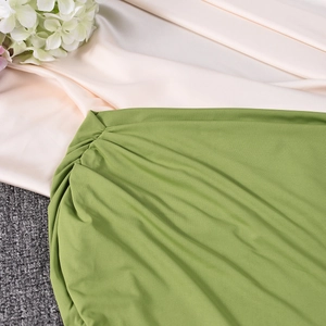 Detail of ruched grass green elastic fabric on a slim fit summer dress with floral accents
