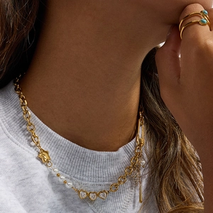 Detail of 18K gold-plated necklace featuring star, pearl, heart and cross charms