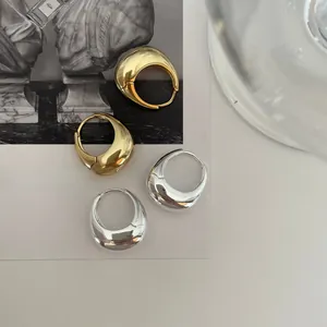 Close-up of sleek gold and silver teardrop hoop earrings with high polish finish
