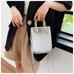 Close-up of silver crocodile pattern tote featuring a unique gold snake-shaped handle