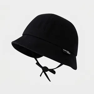 Detail of kids black cotton sun hat featuring adjustable chin strap and side brand label