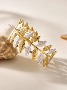 Dettaglio macro del bracciale rigido bicolore oro e argento con motivo a foglia