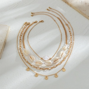 Detail of layered gold necklaces with white seashell, starfish pendant and link chain