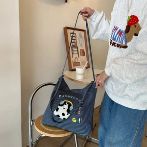 Blue striped canvas tote bag with puppy embroidery shown in a lifestyle casual setting