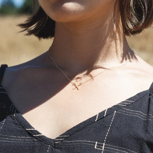 Collier minimaliste plaqué or avec pendentif en forme de X porté par un mannequin femme