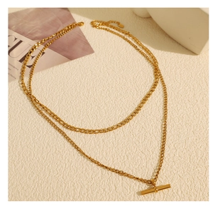 Détail de colliers Figaro dorés superposés avec un fermoir en T élégant en pendentif