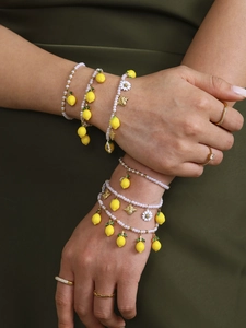 Detail of layered pearl bracelet with lemon pendants and gold rings on model