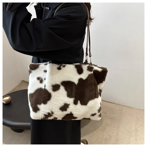 Close-up of fluffy cow print tote bag featuring soft faux fur texture and slim shoulder strap