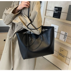 Classic black leather tote bag shown on a model's shoulder for size reference