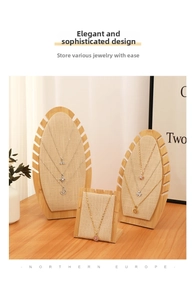 Linen necklace display stands with bamboo bases on a wooden table in a home setting