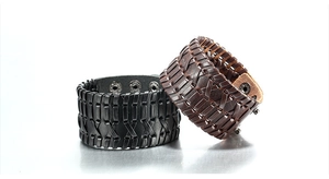 Close-up of black and brown braided leather bracelets with textured metal clasps