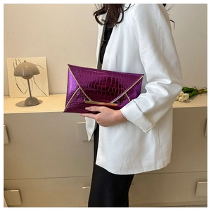 Detailed view of a purple crocodile texture envelope clutch with gold metal buckle