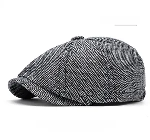 Close-up of light gray herringbone tweed fabric and top button on a newsboy cap
